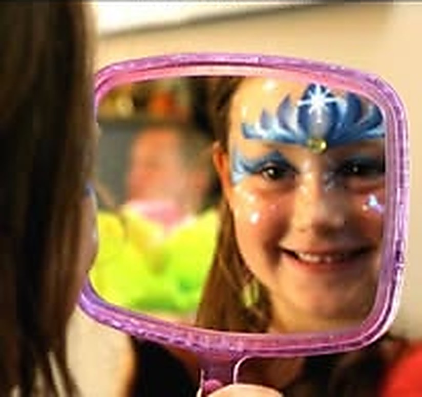 A girl seeing her blue snowflake princess design in a hand mirror